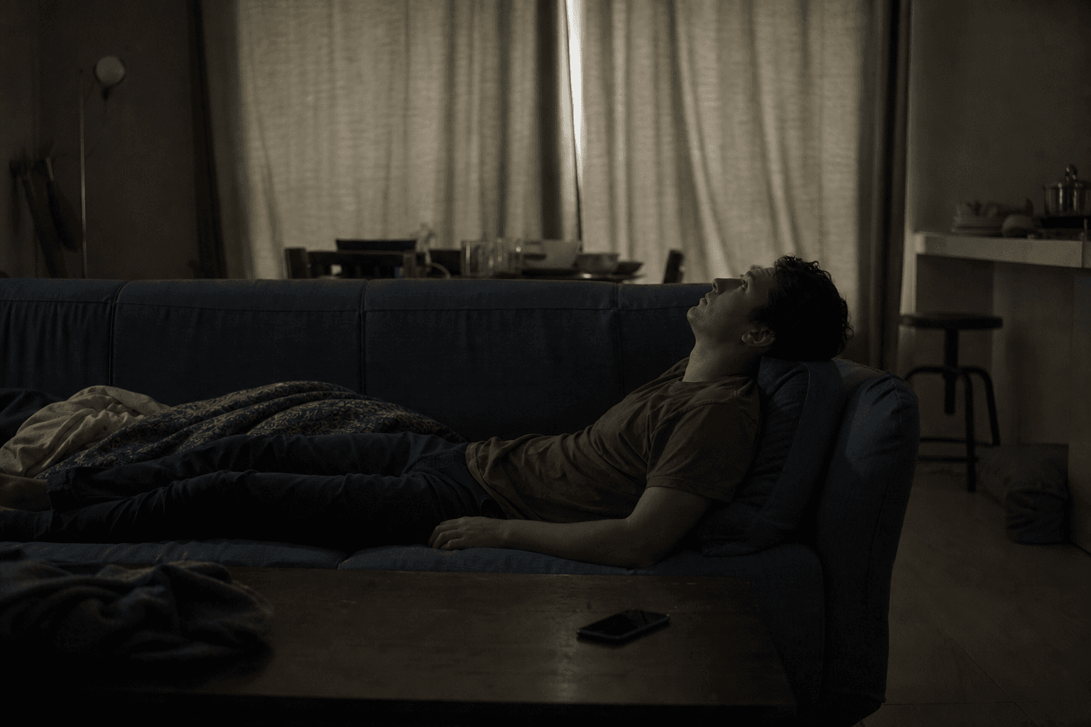 Person lying on couch in dim room staring at ceiling — the pervasive emptiness of clinical depression