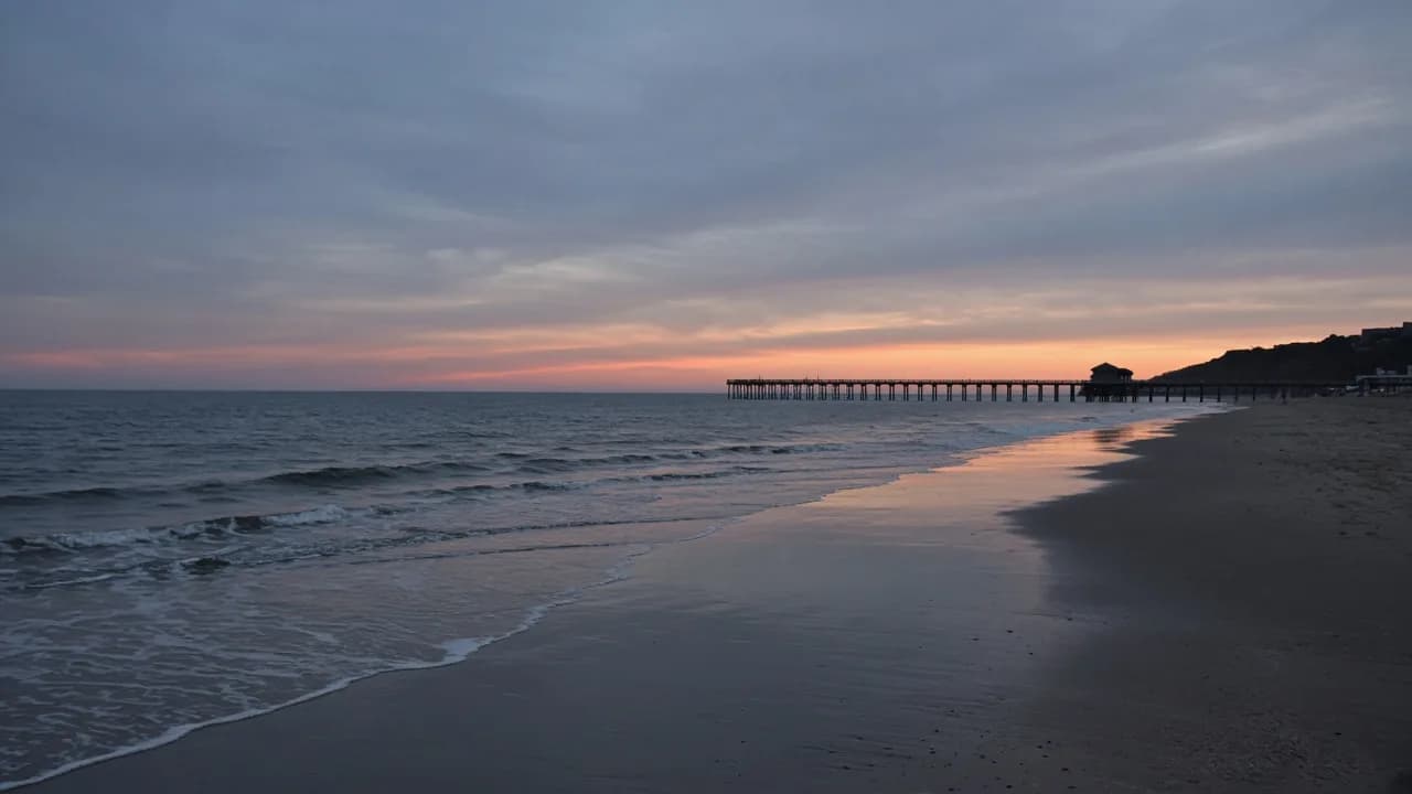 Orange County coastline at dusk with gentle waves and a distant pier