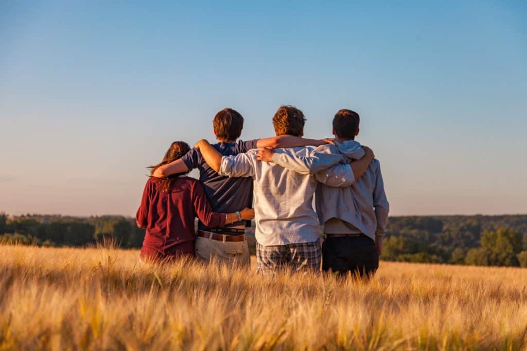 Young men and women embrace in a sunny San Diego field after experiencing the healing benefits of San Diego addiction treatment.