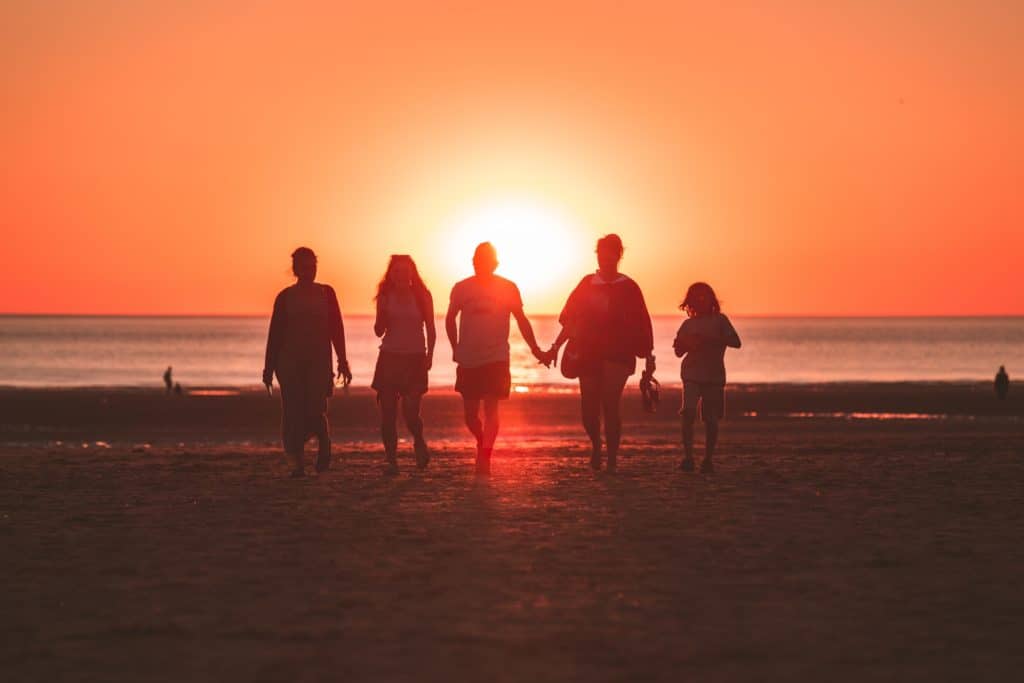 A family walks along a beach into the sunset as they discuss the benefits that family programs had on their familial unit.