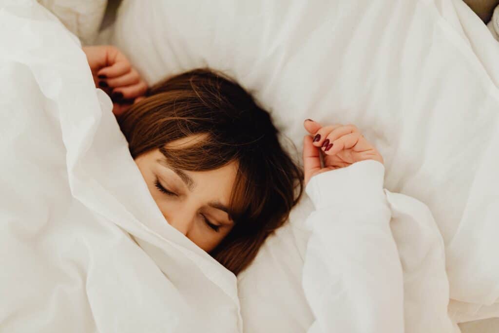 person sleeping with blankets covering their face