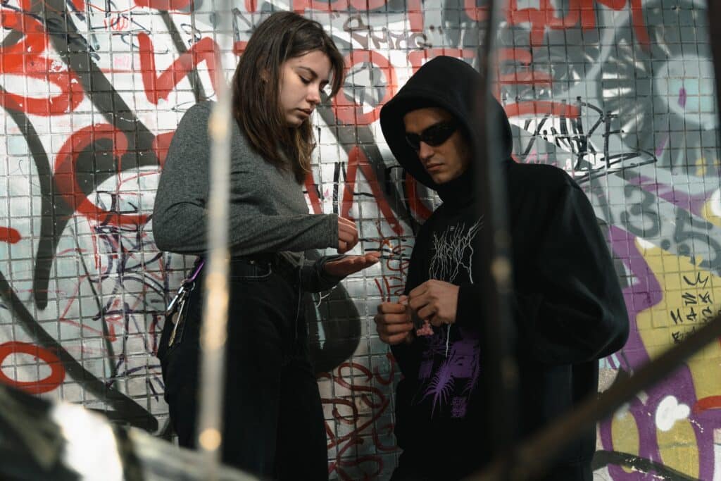 A drug deal in front of a graffiti