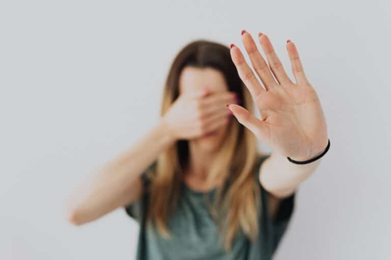 Woman covering her face and holding out her hand